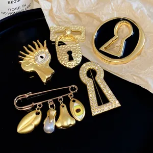 Artistic surrealist gold metal brooches set with sparkling zircon eyes and keyhole shapes