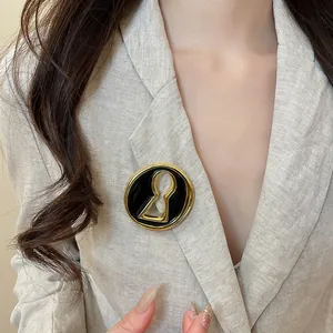 Detail of a chic gold keyhole-shaped brooch pinned on a beige linen blazer lapel