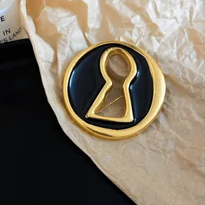 Detailed view of a gold and black enamel brooch featuring a unique keyhole design.