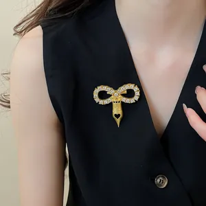 Elegant gold-tone brooch featuring a zircon-studded bow and fountain pen nib on black vest