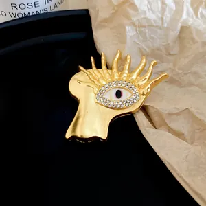 Close-up view of artistic gold metal eye brooch with sparkling clear zircon stone inlay