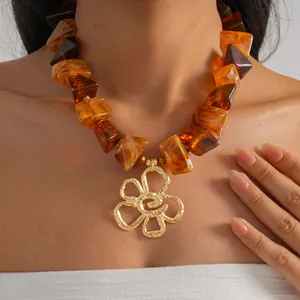 Nahaufnahme einer Vintage-Halskette mit bernsteinfarbenen Acrylperlen und Goldblume