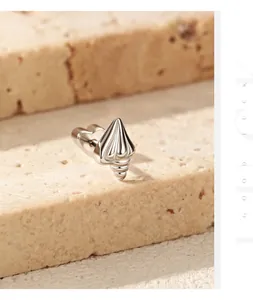 Close-up macro view of S925 sterling silver conch-shaped stud earring on stone surface