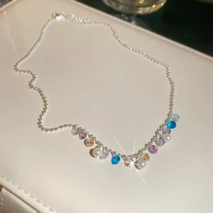 Close-up of sparkling colorful zircon and pearl necklace on a beige leather display box.
