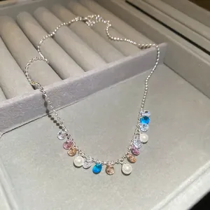 Detail view of a rainbow zircon and pearl necklace in a gray velvet jewelry box