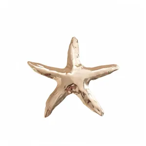 Spilla a forma di stella marina color oro rosa metallizzato su sfondo bianco