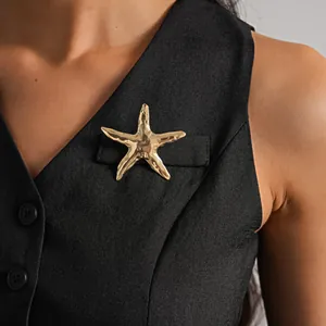 Dettaglio di una spilla a forma di stella marina dorata su un gilet nero professionale