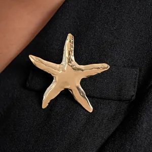 Primo piano di una spilla a forma di stella marina dorata su un bavero nero