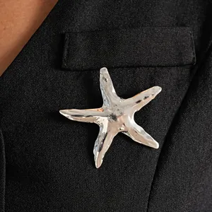 Dettaglio di una spilla a forma di stella marina argentata su un elegante blazer nero
