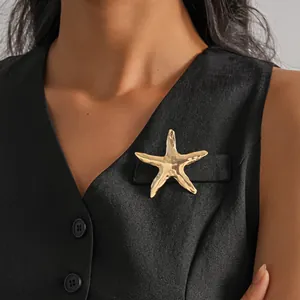 Elegante spilla a forma di stella marina in metallo dorato con trama stropicciata su gilet nero