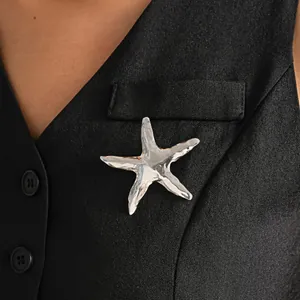 Primo piano di una spilla a stella marina argentata su un gilet nero professionale