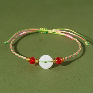 Dettaglio di bracciale in cordino colorato intrecciato a mano con ciambella in calcedonio