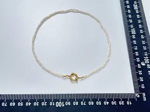 Détail macro du collier de perles d'eau douce avec fermoir doré sur une règle