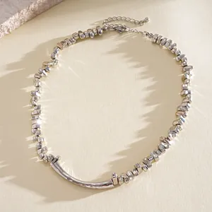 Detailaufnahme der unregelmäßigen silbernen geometrischen Perlen und der gebogenen Metallkette