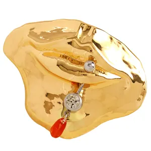 Detailansicht der surrealistischen Goldlippenbrosche mit Kristall und rotem Tropfenanhänger