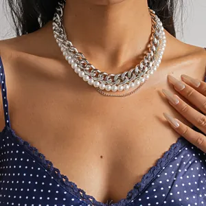 Nahaufnahme einer mehrlagigen Retro-Halskette mit silberner Kette und weißen Perlen.