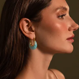 Professional close-up of light blue resin moon hoop earrings worn by a female model profile
