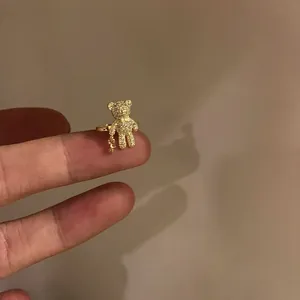 Detailed macro shot of a sparkling crystal-encrusted teddy bear gold ear cuff on a finger