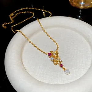Primer plano de un colgante de flor bañado en oro de 24k con circonitas y perla fina