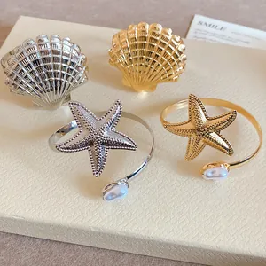 Detailansicht von goldenen und silbernen Seestern- und Muschelarmbändern mit Perlen.