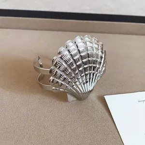Detailansicht eines silbernen muschelförmigen Armreifs mit feinen Rillenstrukturen