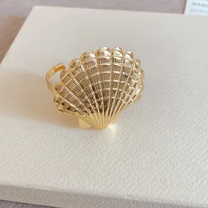 Goldener Armreif in Muschelform mit strukturierter Oberfläche auf weißem Grund