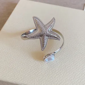 Detaillierte Makroansicht eines silbernen Seestern-Armreifs mit einer eleganten Perle