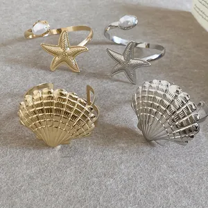 Detailansicht von goldenen und silbernen Muschel- und Seestern-Armreifen auf Filz