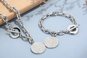 Detail of vintage stainless steel jewelry set with medallion charms and toggle clasp