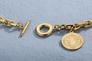 Detailed macro view of gold titanium steel chain with vintage relief coin pendant
