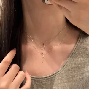 Vue détaillée de colliers dorés superposés avec pendentifs zircons gouttes multicolores