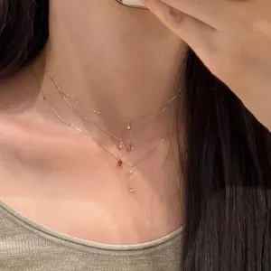 Détail d'un collier triple rang en or orné de charms en zircon coloré en forme de goutte