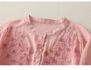 Macro detail of delicate floral butterfly embroidery on pink cotton linen shirt