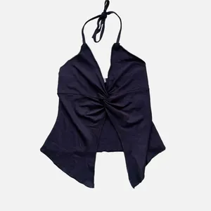 Detail view of black halter neck top with front cross knot and irregular split hemline