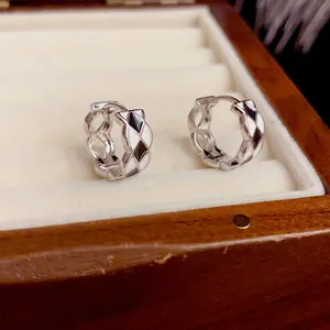 Detail of checkered black and white enamel hoop earrings in a velvet jewelry box