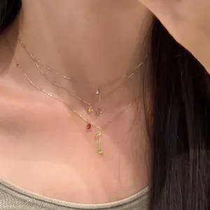 Gros plan d'un collier doré à trois rangs avec des pendentifs en zircon colorés sur un mannequin