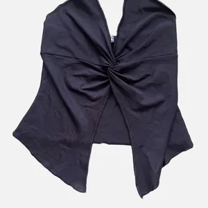 Detail of black halter neck top with twist knot front and irregular hemline