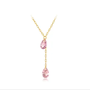 Détail d'un collier en Y doré orné de deux pendentifs en zircone rose en forme de poire