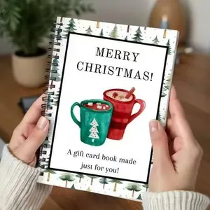 Person holding a Christmas gift spiral notebook with festive mug and tree illustrations