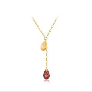 Détail du collier en Y doré avec pendentifs en cristal champagne et rouge profond