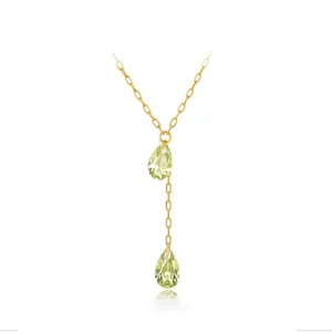 Détail du collier en Y doré avec cristaux vert clair en forme de poire sur fond blanc