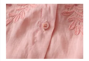 Detailed close-up of pink linen shirt featuring leaf embroidery and a translucent button