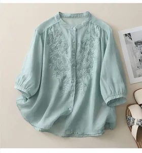 Detail of mint green linen shirt featuring leaf embroidery and white buttons