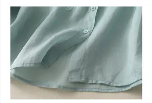 Close-up of mint green linen shirt texture showing stitching and matching buttons