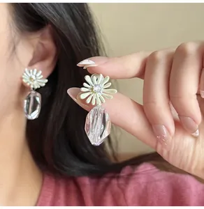 Detail of daisy flower earrings with white enamel petals and faceted crystal drop