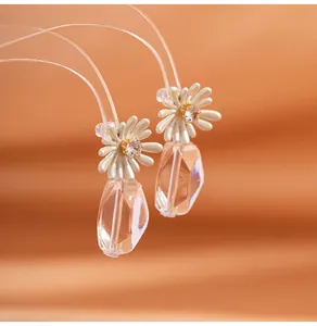 Close-up of white daisy earring with clear crystal drop and clip-on U-shaped backing