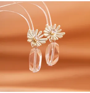 Detailed macro view of white daisy earrings with clear crystal drop and zircon inlay
