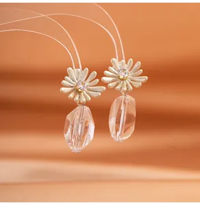 Detailed close-up of cream daisy earrings with sparkling crystal pendants and rhinestones