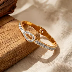 Macro detail of gold spring bangle featuring teardrop zircon setting and hinge clasp