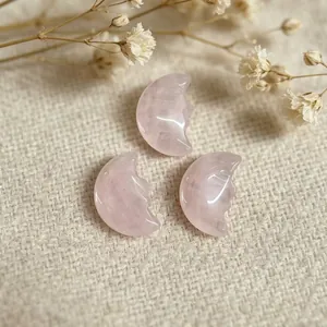Close-up of hand-carved pink rose quartz crescent moon face charms for DIY jewelry making